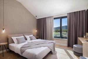 ein Schlafzimmer mit einem Bett und einem großen Fenster in der Unterkunft Luxury Villa Dolac by Trogir and Split, complete privacy in untouched nature with infinity massage heated pool in Marina