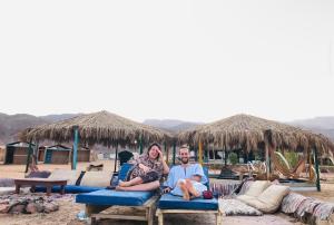 a man and a woman sitting on chairs on a beach at Free Beach Camp in Nuweiba‘ el Muzeinah