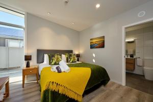 a bedroom with a bed with a yellow blanket at Shearwater Apartments in Kaikoura