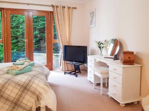 a bedroom with a bed and a desk and a television at The Old Post Office On Loch Tay in Stron-fearnan
