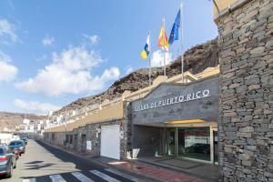 a building with flags on top of it on a street at Las Brisas de Puerto Rico in Mogán