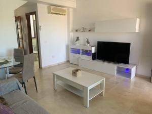 a living room with a flat screen tv and a table at Las Brisas de Puerto Rico in Mogán