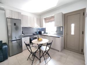 uma cozinha com uma mesa e cadeiras e um frigorífico em Psaromoura Apartment 2 em Agia Pelagia