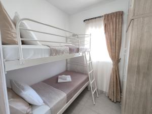 a bedroom with two bunk beds and a window at Psaromoura Apartment 2 in Agia Pelagia