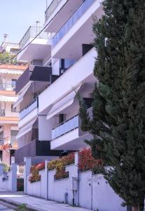 a white building with a fence and a tree at East Coast Senses in Thessaloniki