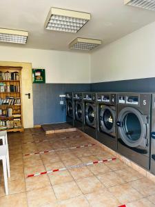 eine Waschküche mit drei Waschmaschinen und Fliesenboden in der Unterkunft Mobil-home COSY clim&tv-3 Chambres in Vic-la-Gardiole