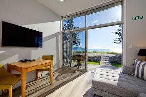 uma sala de estar com uma mesa, um sofá e uma televisão em Shearwater Apartments em Kaikoura