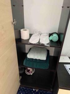ein Schrank mit Handtüchern und Toilettenpapier auf einem Regal in der Unterkunft Cozy & warm studio in Bukarest