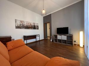 a living room with an orange couch and a flat screen tv at Relax Segrate in Segrate