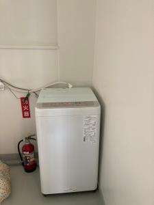 einen kleinen weißen Kühlschrank in einer Ecke eines Zimmers in der Unterkunft Yamagata Guesthouse山形ゲストハウス in Murayama
