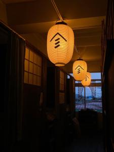 drei Laternen, die von der Decke in einem dunklen Raum hängen in der Unterkunft Yamagata Guesthouse山形ゲストハウス in Murayama