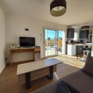 a living room with a coffee table and a kitchen at Studio avec terrasse et jardin à 100 m de la plage in Ploemeur