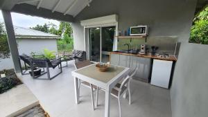 een keuken met een witte tafel en stoelen op een patio bij LE MANGUIER in Baie-Mahault