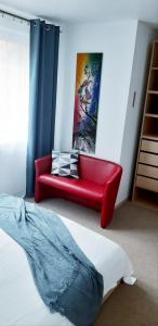 ein rotes Sofa in einem Zimmer mit einem Bett in der Unterkunft Ievos Kalno Apartamentai in Juodkrantė