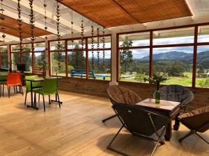 蘇埃斯卡的住宿－Coclí Glamping Suesca，用餐室设有桌椅和窗户。