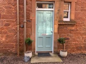 a blue door on a brick building with two plants at The Beach Pad North Berwick in North Berwick