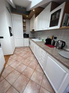 una cucina con armadietti bianchi e pavimento piastrellato di Ai Cappuccini, Trento a 360 gradi a Trento