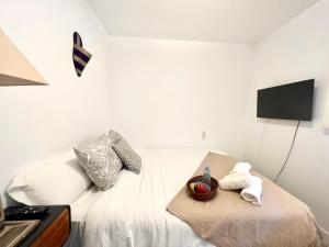 sypialnia z białym łóżkiem i telewizorem na ścianie w obiekcie Apartamento estilo árabe en el centro De San Pedro de Alcántara - Toledo 1b w Marbelli