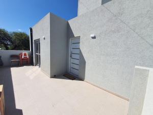 ein weißes Gebäude mit einer Tür und einer Terrasse in der Unterkunft Departamento en Arroyito- Córdoba in Arroyito