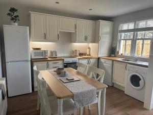 una cucina con elettrodomestici bianchi e un tavolo con sedie di Denburn Cottage, East Neuk of Fife a Colinsburgh