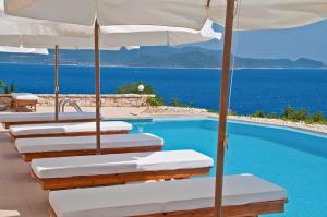 a row of lounge chairs with umbrellas next to a swimming pool at Lycia Hotel in Kaş