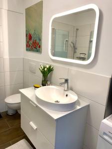 a white bathroom with a sink and a mirror at Helles Apartment über den Dächern Rostocks in Rostock