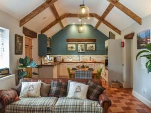 a living room with a couch and a kitchen at Mudhorse Cottage in Stolford