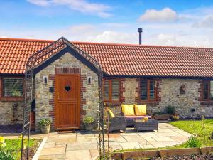 a stone house with a wooden door and a patio at Mudhorse Cottage in Stolford