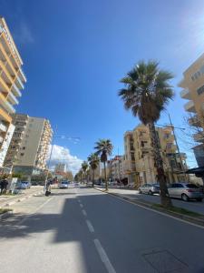 an empty street with a palm tree and buildings at The Blue Pearl Apartment in Durrës