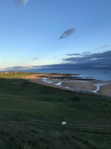 - une vue sur un parcours de golf et l'océan dans l'établissement Denburn Cottage, East Neuk of Fife, à Colinsburgh