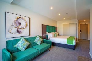 ウェリントンにあるThe Sebel Wellington Thorndonのベッドと緑のソファが備わるホテルルームです。