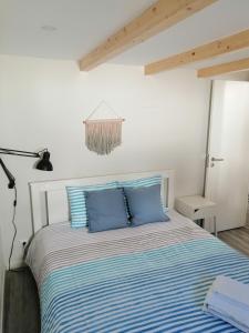 a bed with blue pillows in a white room at Casa da Villa in Vila do Bispo