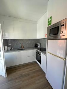 a kitchen with white cabinets and a white refrigerator at RETIRO 401 one-bedroom apartment in Guimarães