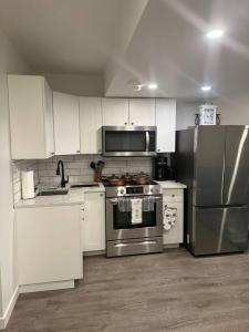 uma cozinha com armários brancos e um frigorífico de aço inoxidável em Brand new 1 Bedroom Basement Suite. Wi-Fi,Netflix em Edmonton