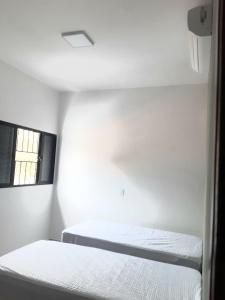 a white room with two beds and a window at Sobrado 2 com Jacuzi e Churrasqueira in Brotas