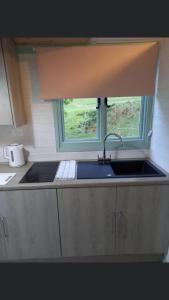 uma cozinha com um lavatório e uma janela em Shepherds hut above mawddach estuary em Dolgellau