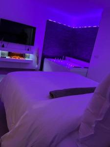 una camera da letto con letto bianco e illuminazione viola di La suite a Castelnau-le-Lez