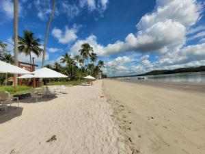 a sandy beach with chairs and umbrellas on it at Praia dos Carneiros Flat 120-CM Eco Resort - ao lado da igrejinha in Tamandaré