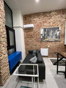 a living room with a couch and a brick wall at Moderno y luminoso departamento. in Madrid