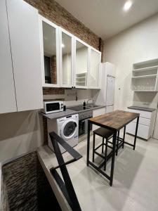 a kitchen with white cabinets and a table with chairs at Moderno y luminoso departamento. in Madrid