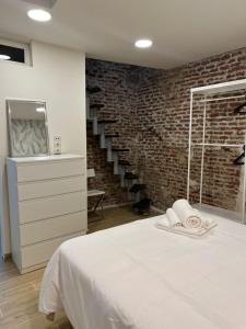 a white bed in a room with a brick wall at Moderno y luminoso departamento. in Madrid