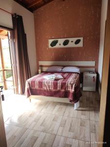 um quarto com uma cama e piso em madeira em Pousada Natureza e Arte em Cunha