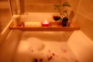 a bath tub with a candle and two glasses of wine at Gold Coast Photography Inn in Estoril