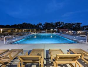 a swimming pool with lounge chairs around it at night at Salty Kisses - Let The Beach Reconnect Your Souls in Corolla