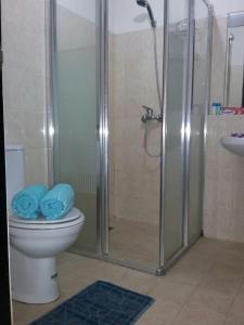 a bathroom with a shower and a toilet with blue towels at The Wave Apartment in Jakarta