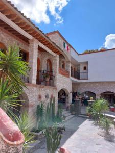 une grande maison en pierre avec une cour ornée de cactus dans l'établissement Hotel Casa Caro, à Bernal