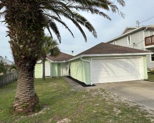 a house with a garage and a palm tree at Beautiful House Sleeps 12 - Hot Tub - Walk to Beach in Panama City Beach