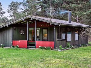 ロービュにあるHoliday home Rødby XXIの赤い扉と緑の庭のある小さな家