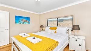 a bedroom with a bed with a yellow blanket at Tanapaser in Currarong