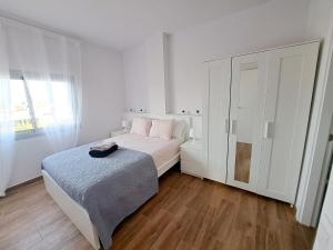 a white bedroom with a bed and a cabinet at Sky Puerto in Puerto del Rosario